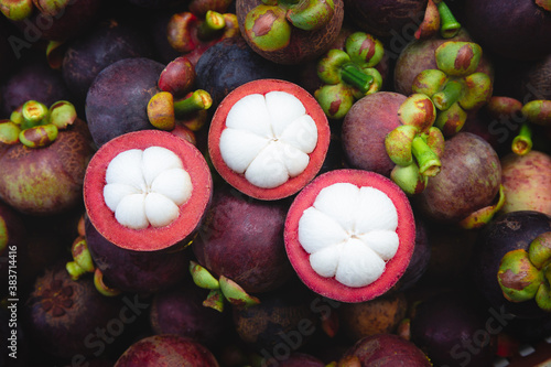 Fresh ripe mangosteen fruits and cross section showing the thick purple skin and white flesh. photo