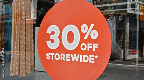 Red sign hanging on a glass window with the inscription 30% off