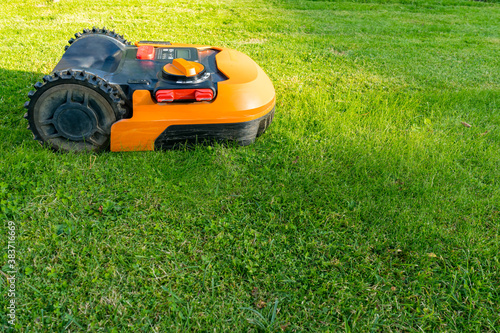 Orange robotic lawn mower makes green lawn perfect