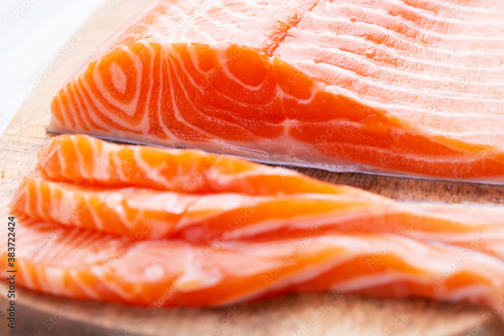 Raw fresh salmon fillet cut into slices and piece on wooden board Raw fresh salmon fillet cut into slices and piece on wooden board
