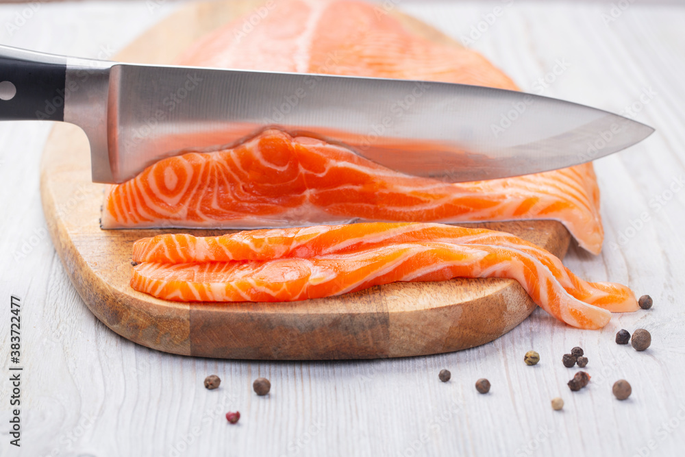 Knife cuts slices of fresh raw salmon Knife cuts slices of fresh raw salmon