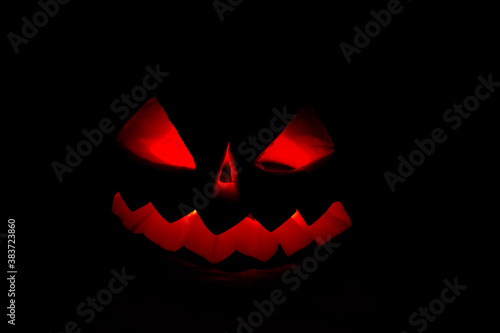 Spooky Halloween pumpkin jack-o-lantern with burning candles on dark background