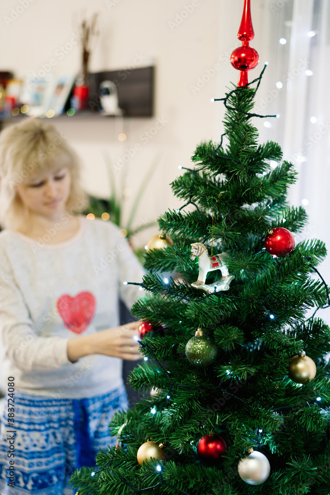 Close-up of a decorated Christmas tree and a blurry girl in the background decorating it.