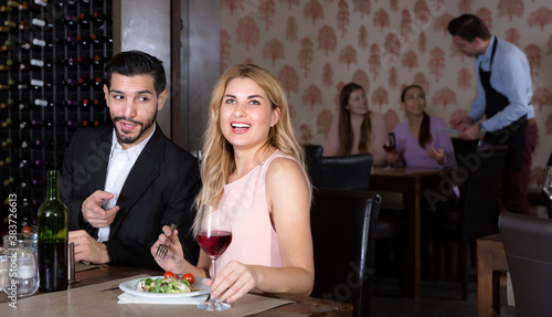 Loving happy positive pair enjoying evening meal and conversation in cozy restaurant