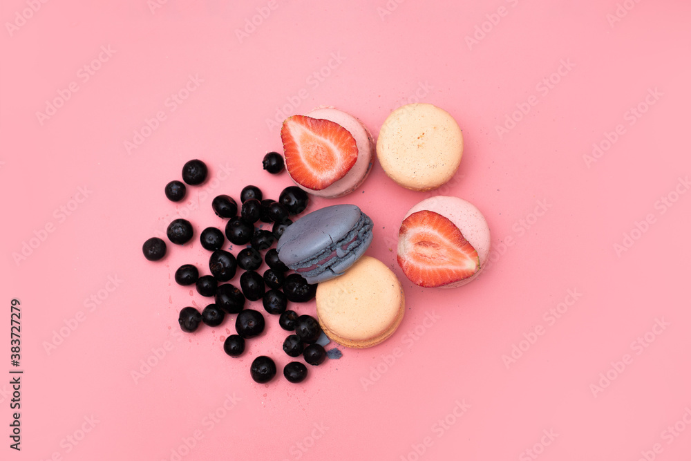 five macaroons of different colors are laid out in a circle and decorated with strawberries and blueberries on a pink background, top view five macaroons of different colors are laid out in a circle and decorated with strawberries and blueberries on a pink background, top view