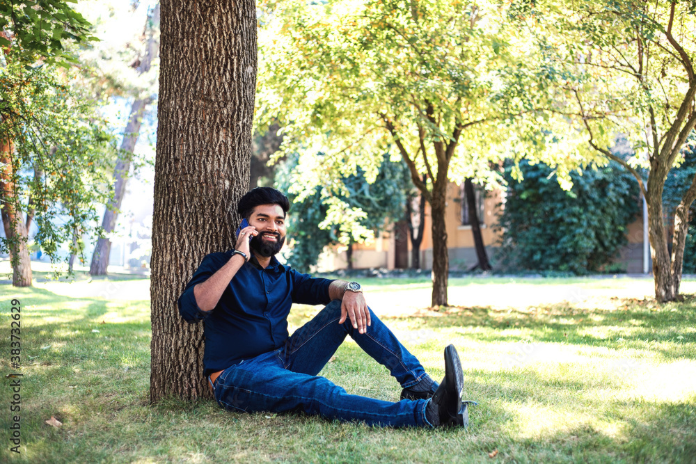 Young Indian man talking by phone in the park. Young Indian man talking by phone in the park.