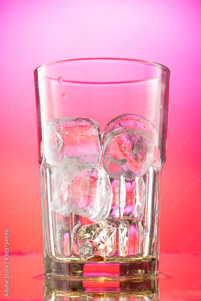 pieces of pure real ice in a glass on a colored gradient background, cubes are rounded pieces of pure real ice in a glass on a colored gradient background, cubes are rounded