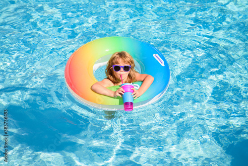 Child with cocktail on watter pool in the summer. Cute funny little toddler boy in sunglasses relaxing with toy ring floating in a pool having fun during summer vacation.