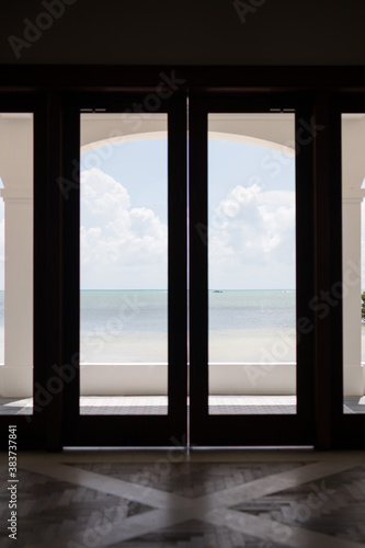 Calm beach ocean water texture sand captured and framed by a large grand timber door frame entry way picture holiday travel tourist