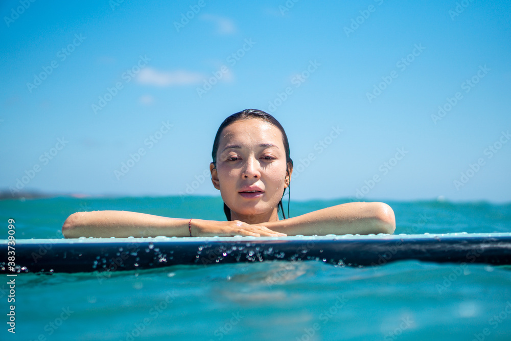 Portrait of surfer girl on surf board in blue ocean