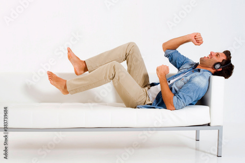 man on the couch listening music with headphones photo