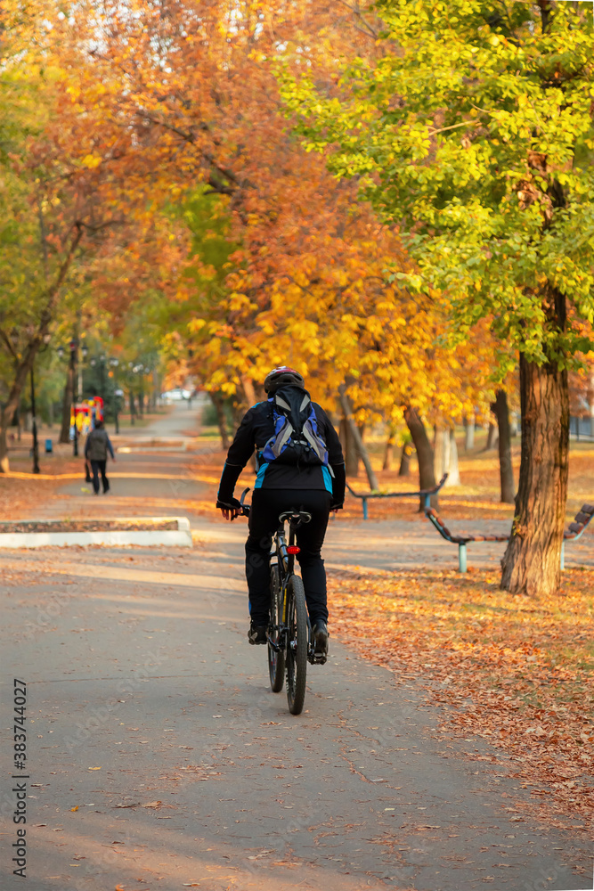 Saratov, Russia - 10/04/2020: Active healthy lifestyle, leisure sports, cyclist man rides a bicycle along the path in the park in the city along the street in autumn outdoors on a sunny warm day