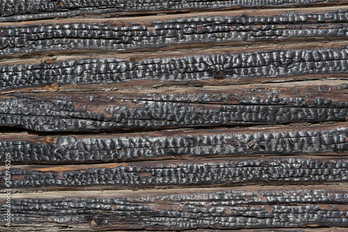 Close-up of charred walls of a wooden blockhouse. The old charred wall of the house. Horizontal lines. Wood wall texture after fire