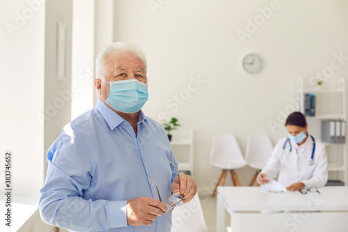 Portrait of a senior retired man in a protective medical mask on a background of a doctor.