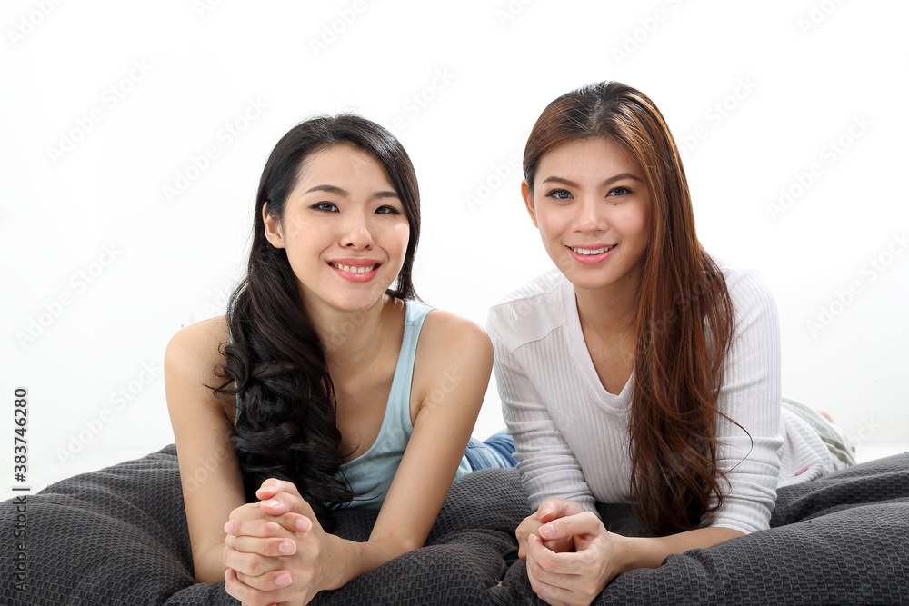 Two Beautiful young south east Asian Chinese relax pillow cushion look at camera on white Two Beautiful young south east Asian Chinese relax pillow cushion look at camera on white