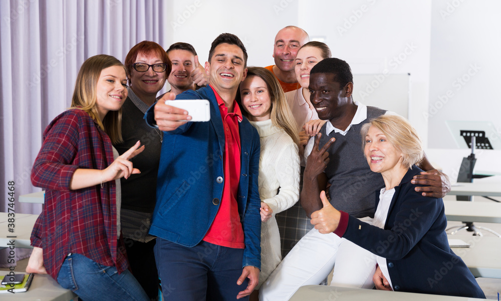 Multinational group of of happy adult students taking selfie in auditorium