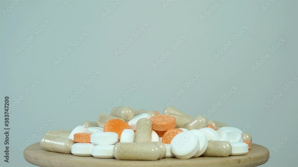 4K view of a bunch of colored pills rotating on a wooden surface 4K view of a bunch of colored pills rotating on a wooden surface