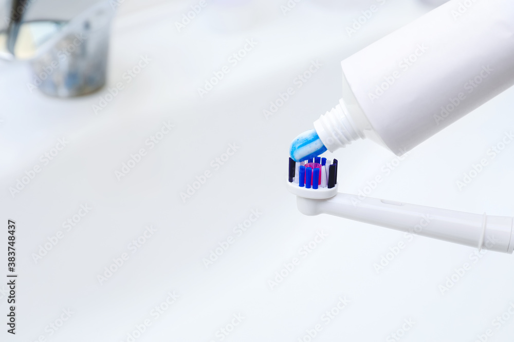 Squeezing of paste on tooth brush in bathroom, closeup
