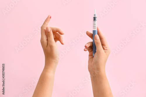 Female hands with blood drop and syringe on color background. Diabetes concept photo