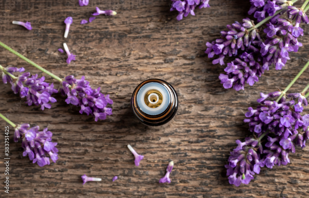 A bottle of lavender essential oil with blooming lavender twigs A bottle of lavender essential oil with blooming lavender twigs
