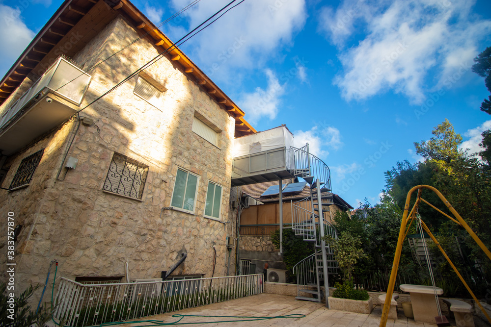 Obraz premium A small and narrow sukkah at the entrance to a beautiful two-story house in Jerusalem, Israel.