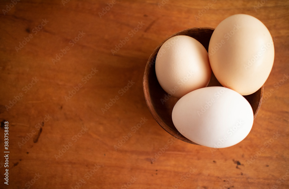 Three fresh white eggs in a wooden cup on a wooden table
木製テーブルの上にある木のカップに入った３つの白い卵 1