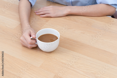 Coffee latte in holding hand business woman on wooden desk.