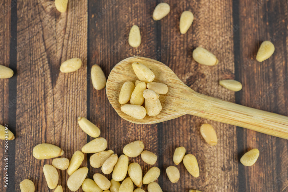Many pine nuts with wooden spoon and wooden background, top view Many pine nuts with wooden spoon and wooden background, top view
