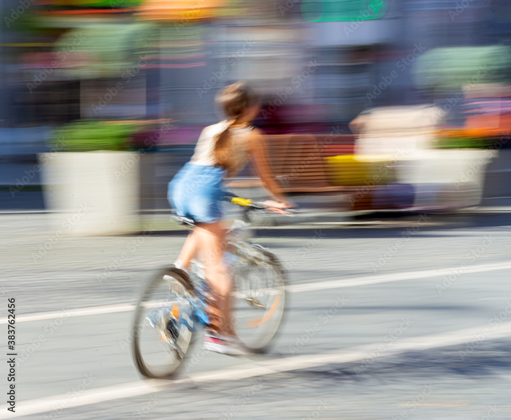 Woman on bicycle in motion riding down the street