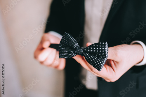 Groom holds a bowtie in his hands, gets dressed and prepares for the wedding ceremony.