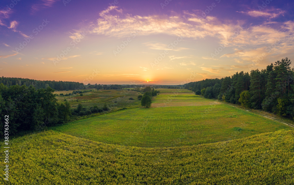 Obraz premium Rural landscape in the evening with a beautiful burning sky. Aerial view. Panoramic view of pine forest, fields during sunset