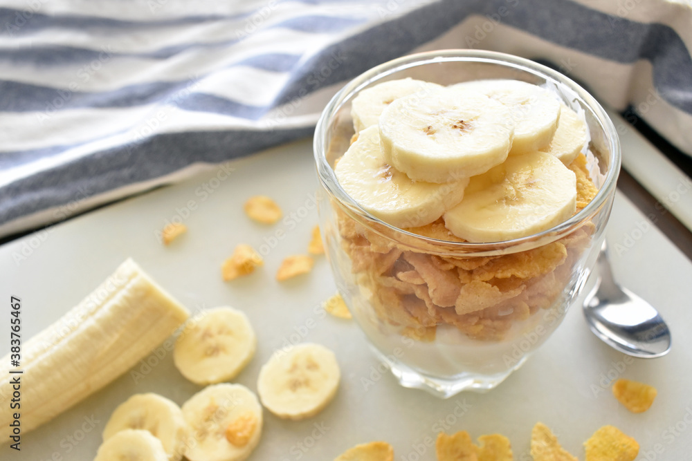 Greek yogurt, corn flakes cereal and sliced banana in a glass. Healthy breakfast. Dietary and weight loss control program. Copy space is on the left side on the blurry part of photo. Greek yogurt, corn flakes cereal and sliced banana in a glass. Healthy breakfast. Dietary and weight loss control program. Copy space is on the left side on the blurry part of photo.