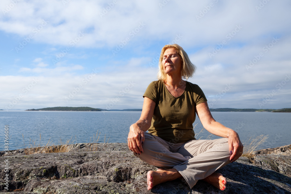 Seinor woman relaxing and meditating outdoors by the sea on a summer day Seinor woman relaxing and meditating outdoors by the sea on a summer day