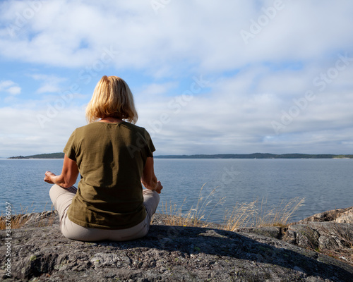 Seinor woman relaxing and meditating outdoors by the sea on a summer day photo