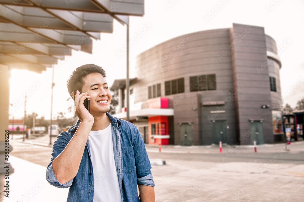 Happy Asian man using a smartphone on the corner of the road, Smiling man using a mobile phone on the street Happy Asian man using a smartphone on the corner of the road, Smiling man using a mobile phone on the street