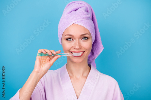 Photo of pretty young lady brushing teeth preparing wear purple towel turban bath robe isolated blue color background