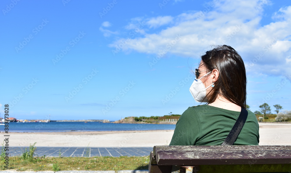 Woman with Covid-19 face mask on a beach. KN95 or N95 or FFP2 mask.