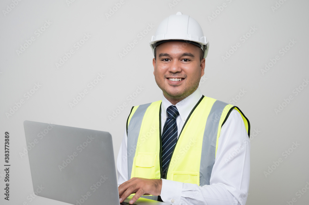 Asian civil engineer operate with laptop to control working in studio. Worker wearing hard hat using laptop computer standing on isolated white background.. Asian civil engineer operate with laptop to control working in studio. Worker wearing hard hat using laptop computer standing on isolated white background..