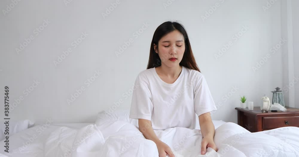Young Asian women are not feeling well after waking up and sitting in bed, coughing, sneezing and runny nose. Young Asian women are not feeling well after waking up and sitting in bed, coughing, sneezing and runny nose.