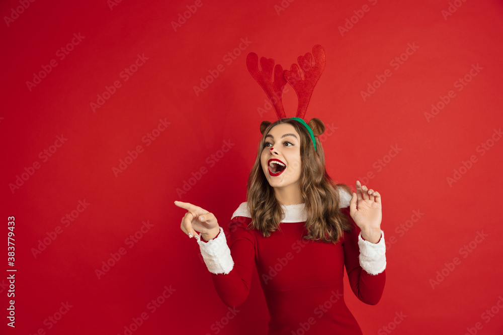Pointing. Greetingcard. Concept of Christmas, 2021 New Year's, winter mood, holidays. Copyspace for ad, postcard. Beautiful caucasian woman with long hair like Santa's Reindeer catching giftbox. Pointing. Greetingcard. Concept of Christmas, 2021 New Year's, winter mood, holidays. Copyspace for ad, postcard. Beautiful caucasian woman with long hair like Santa's Reindeer catching giftbox.
