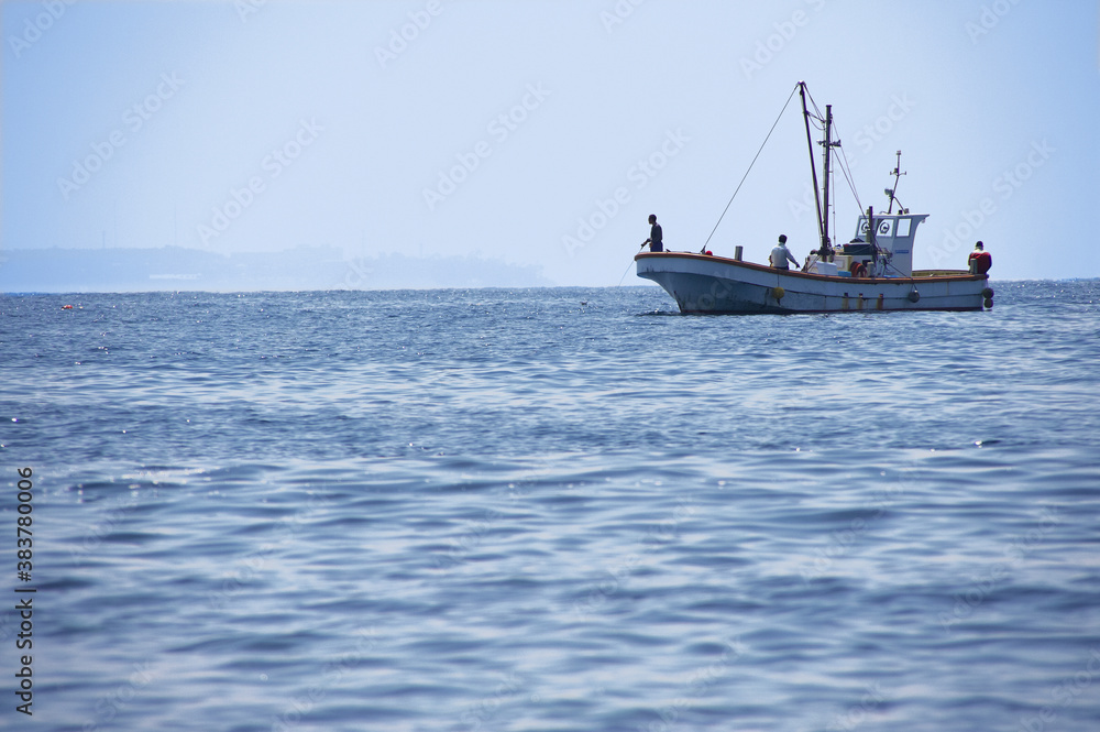 岬の沖で釣り糸を垂らす釣り船