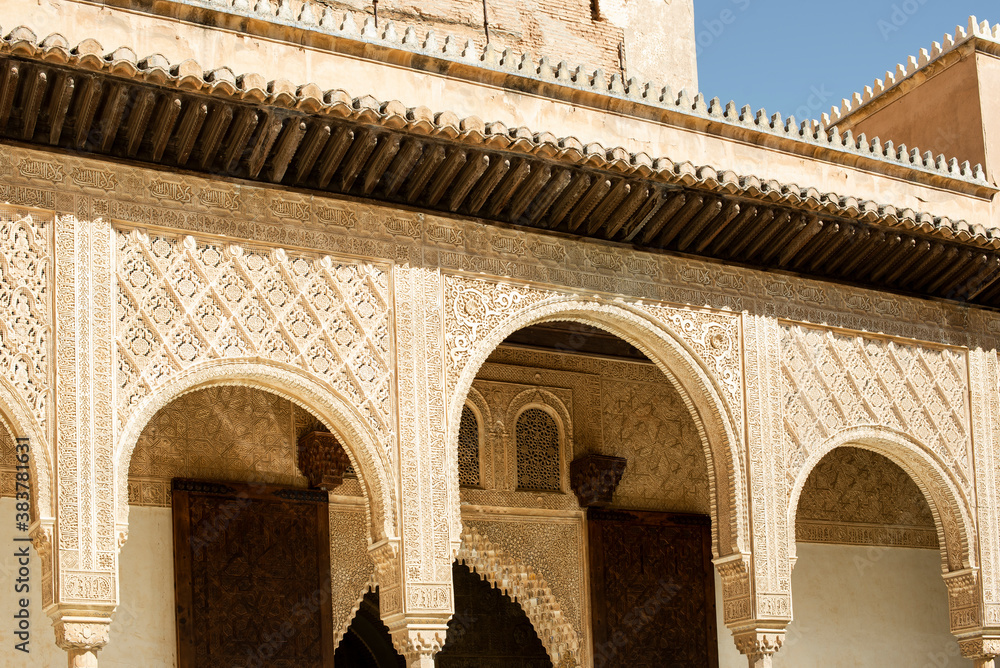 Beautiful architecture with an arch wooden door in the Moorish style at Nasrid Palace, Alhambra.