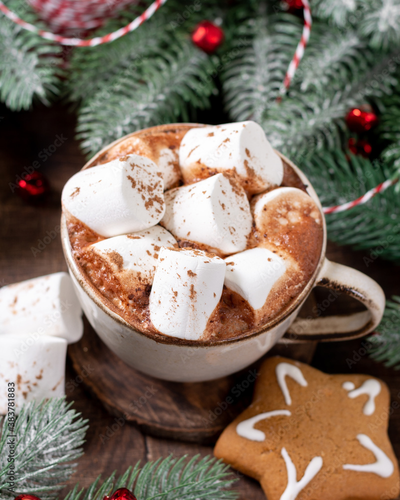 Hot cocoa or hot chocolate with marshmallows in a ceramic cup surrounded by gingerbread, Christmas tree branches and decorations on a brown wooden table. New Year or Christmas flatly Hot cocoa or hot chocolate with marshmallows in a ceramic cup surrounded by gingerbread, Christmas tree branches and decorations on a brown wooden table. New Year or Christmas flatly