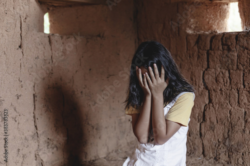 girl crying in despair sitting against wall. human trafficking concept. dark portrait