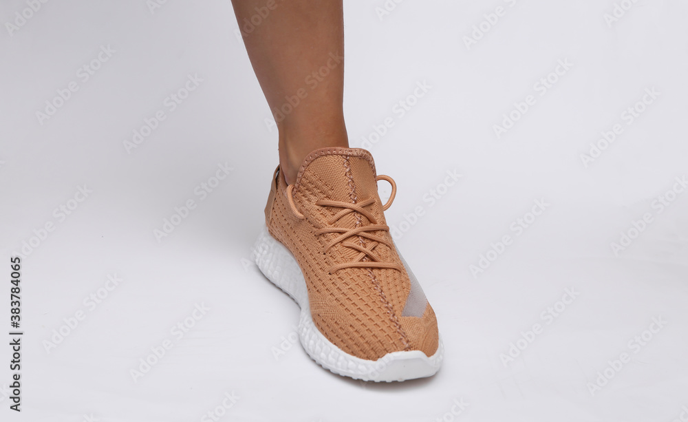 Female feet in trendy sports shoes on white background Female feet in trendy sports shoes on white background