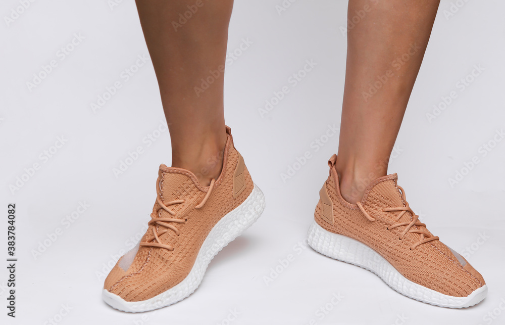 Female feet in trendy sports shoes on white background Female feet in trendy sports shoes on white background