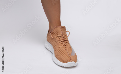 Female feet in trendy sports shoes on white background