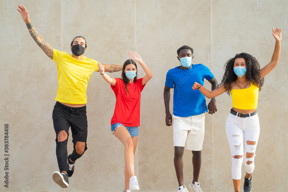 Millennial people jumping . Young friends with protective masks for coronavirus. Virus and friendship concept.