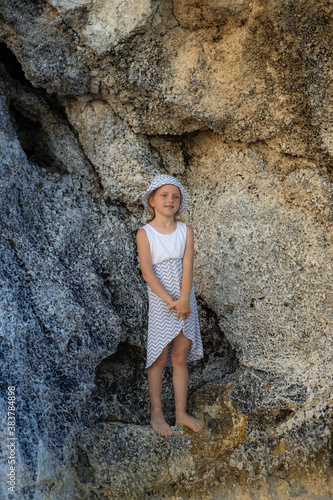Cute little girl standing between the rocks. Caucasian girl wearing dress and hat. Happy childhood. Summer concept. Traveling with kid. Bali  Indonesia