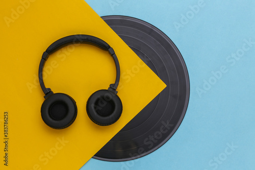Retro vinyl record and stereo headphones on yellow blue background. Top view. Flat lay